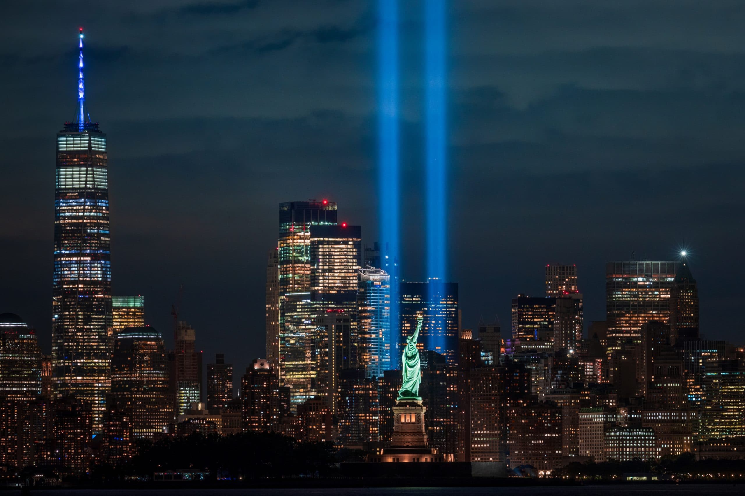 Tribute in Light remembers the September 11 terrorist attacks with Statue of Liberty in foreground.