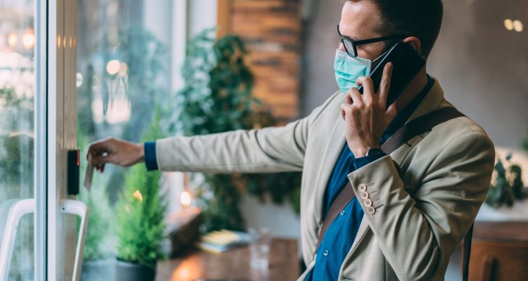 A Man In A Face Mask Uses A Touchless Entry System To Securely Enter The Workplace